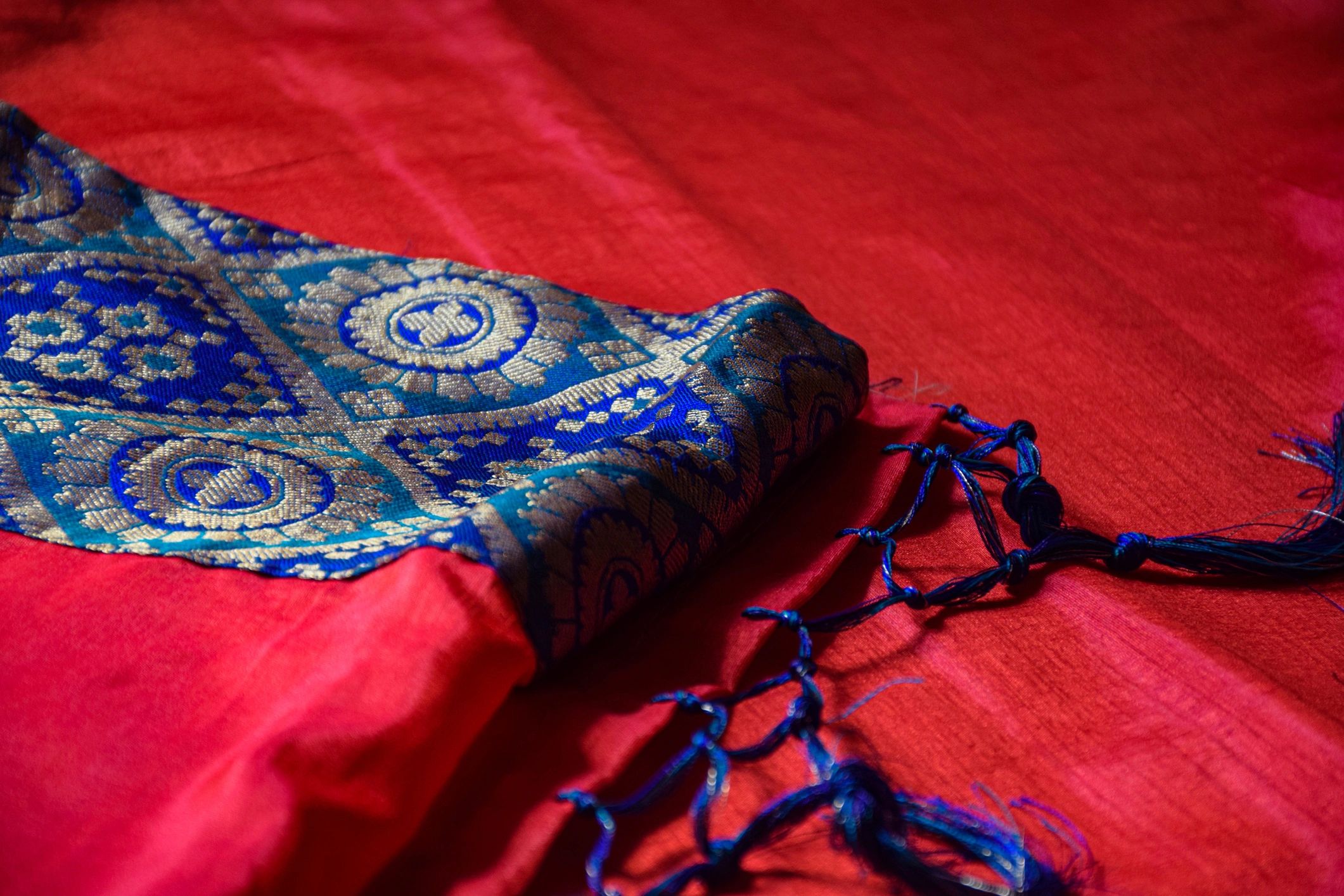 Close-up of a red silk saree with blue and gold border